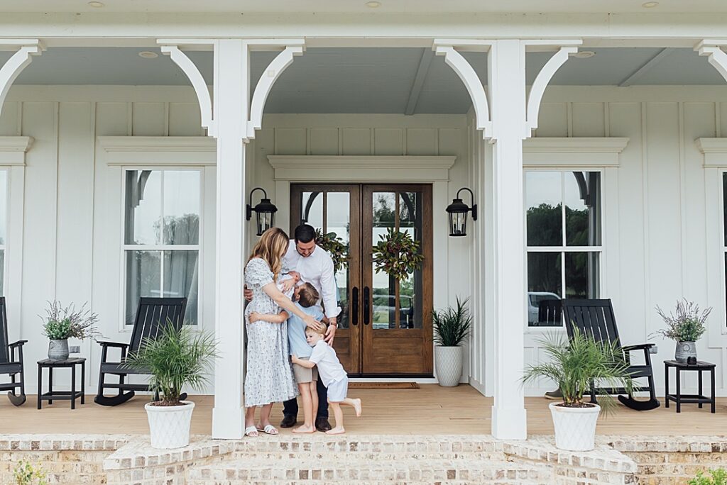 Candid family on porch at newborn session with three boys.